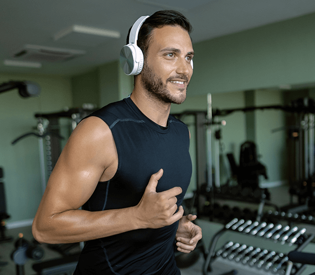 smiling-athletic-man-running-treadmill-while-exercising-gym