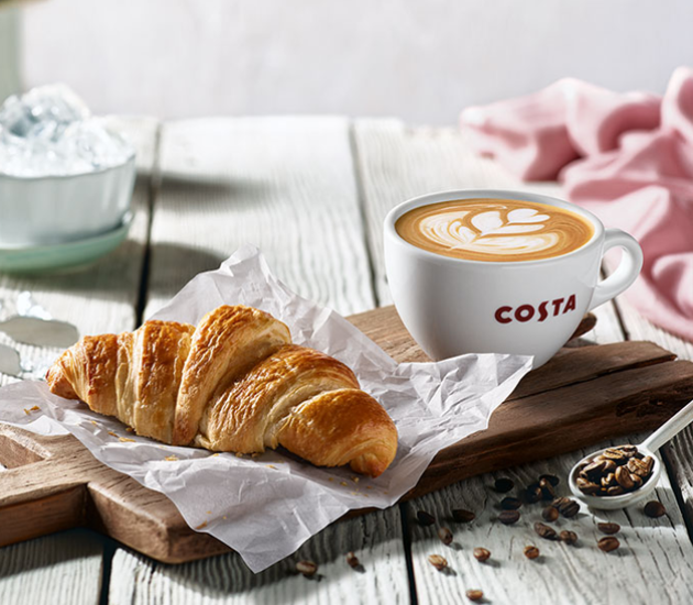 croissant i kawa w filiżance Costa na drewnianym stole